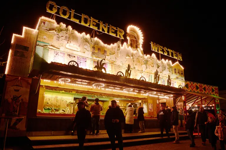 Hell erleuchtete nostalgische Schießbude Goldener Westen bei Nacht im Außenbereich des Winterspektakels Hamburg