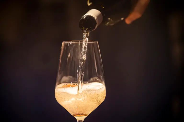 Schaumwein wird beim Empfang in ein Glas eingeschenkt