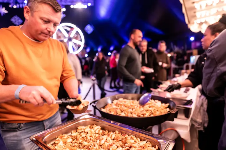 Servicekraft richtet beim Dinner im Food Court Teller am Buffet an
