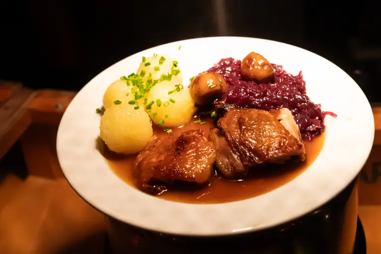 Angerichteter Teller mit Entenkeule, Rotkohl und Kartoffelklößen aus dem Food Court