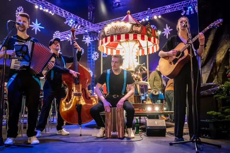 Live-Band spielt zwischen Karussell und Fahrgeschäften im Kuppelzelt des Winterspektakels